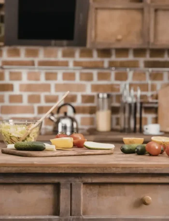 Bancada de cozinha com diversos vegetais coloridos e potes de vidro organizados para o preparo de refeições.