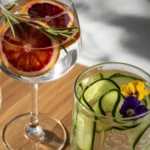 Gin Tônica servido em taça de balão com fatias de pepino e especiarias, o ápice do frescor.